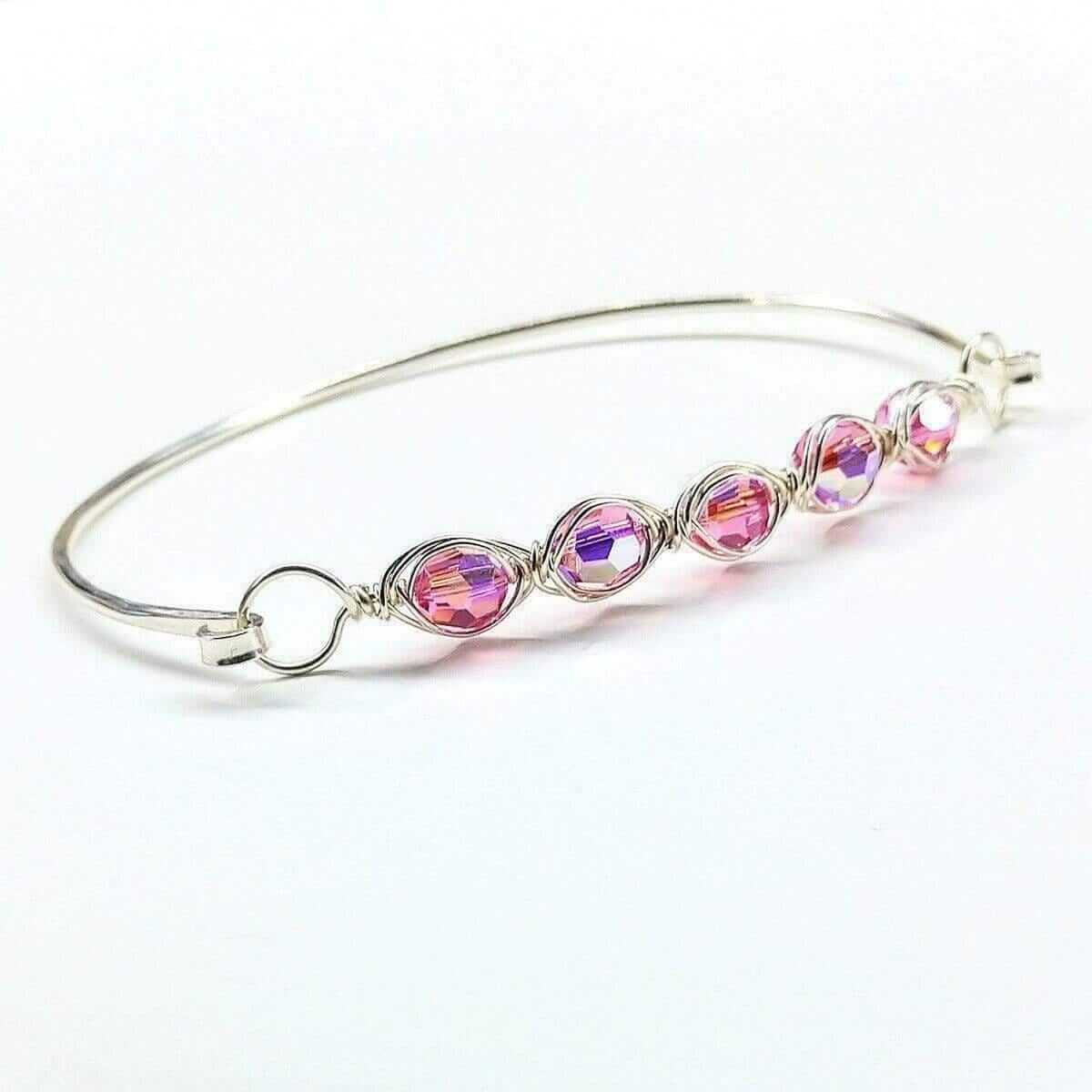 Silver bangle with pink and purple crystal beads on a white background