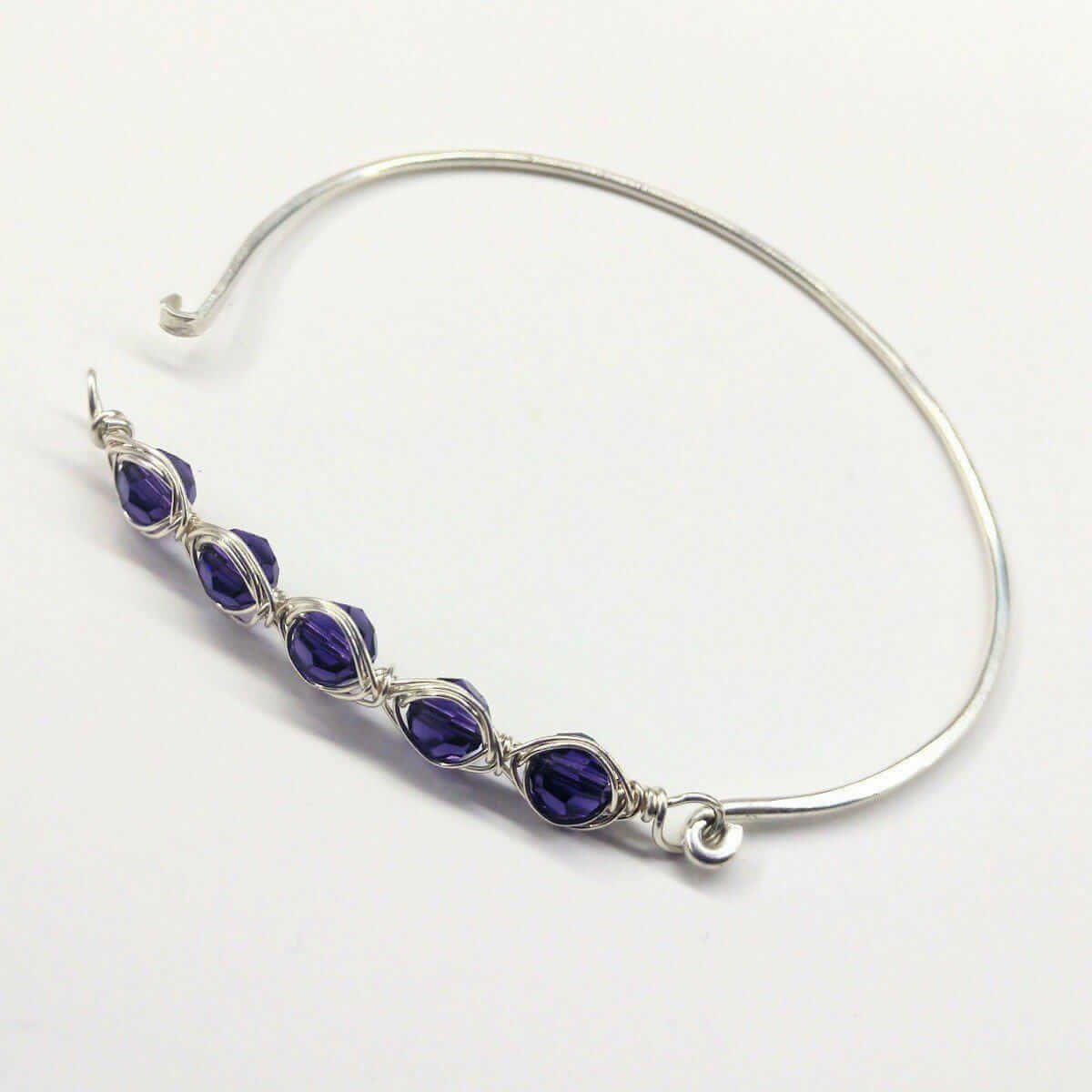 Silver bangle with purple beads on a white background