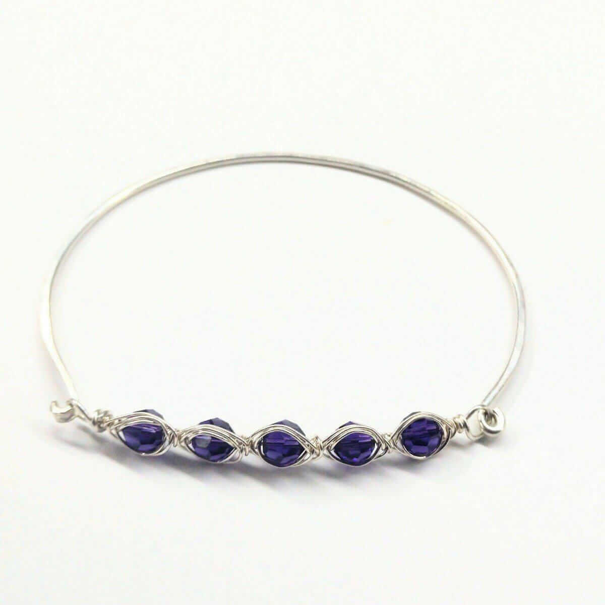 Silver bracelet with purple gemstones on a white background