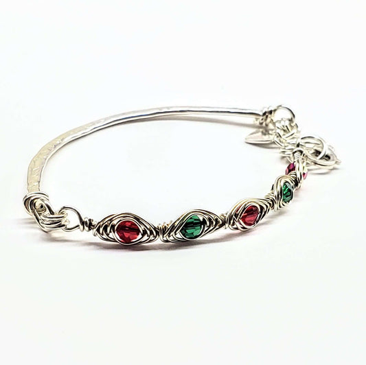 Silver bracelet with red and green gemstones on a white background