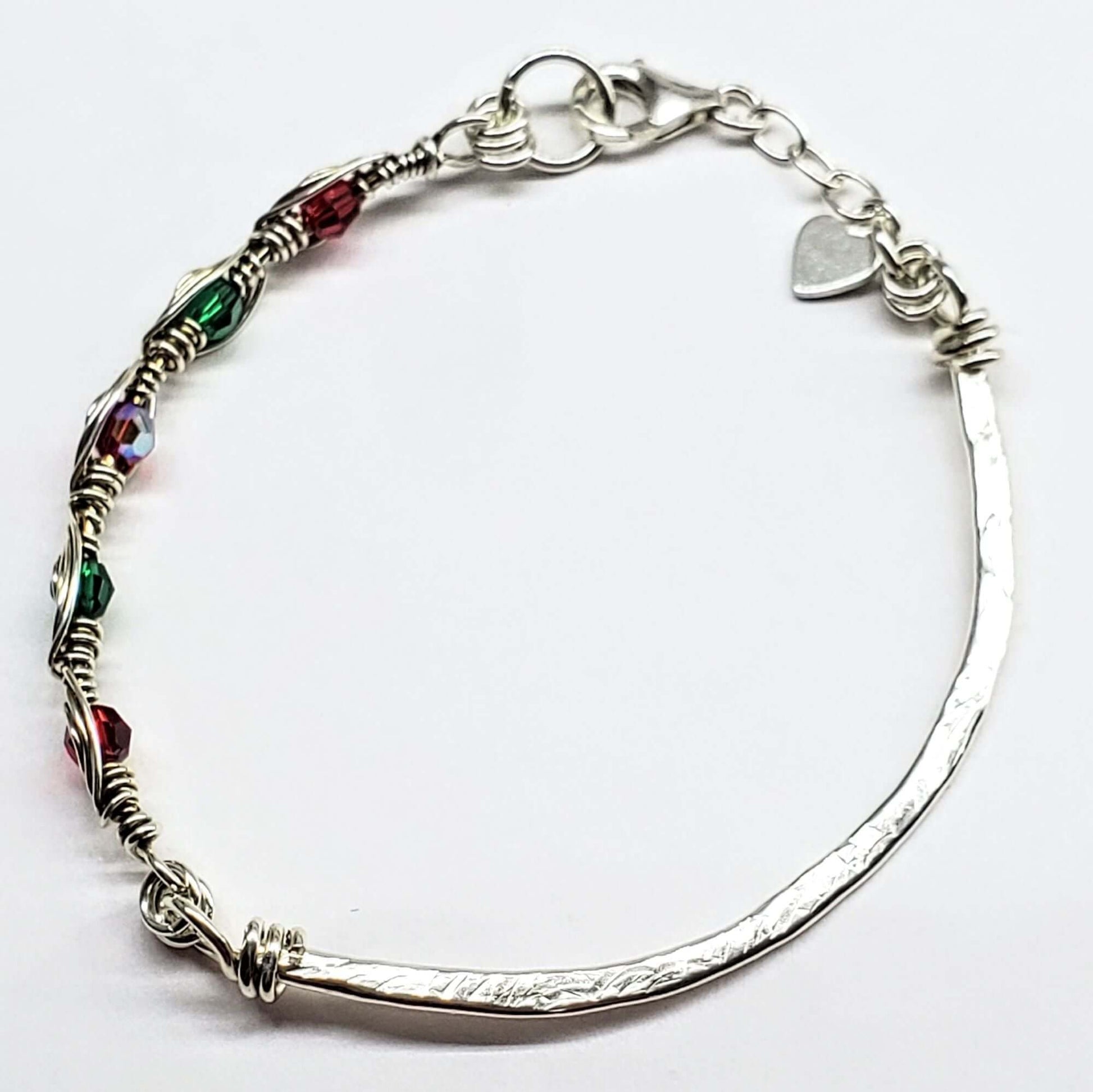 Silver bracelet with colorful beads and a heart charm on a white background
