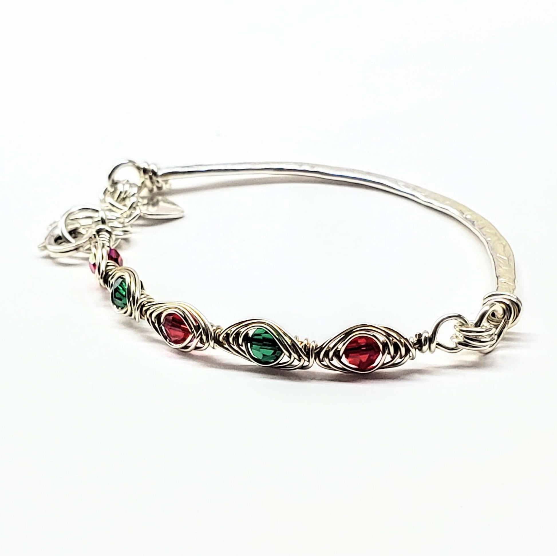 Silver bracelet with red and green gemstones on a white background