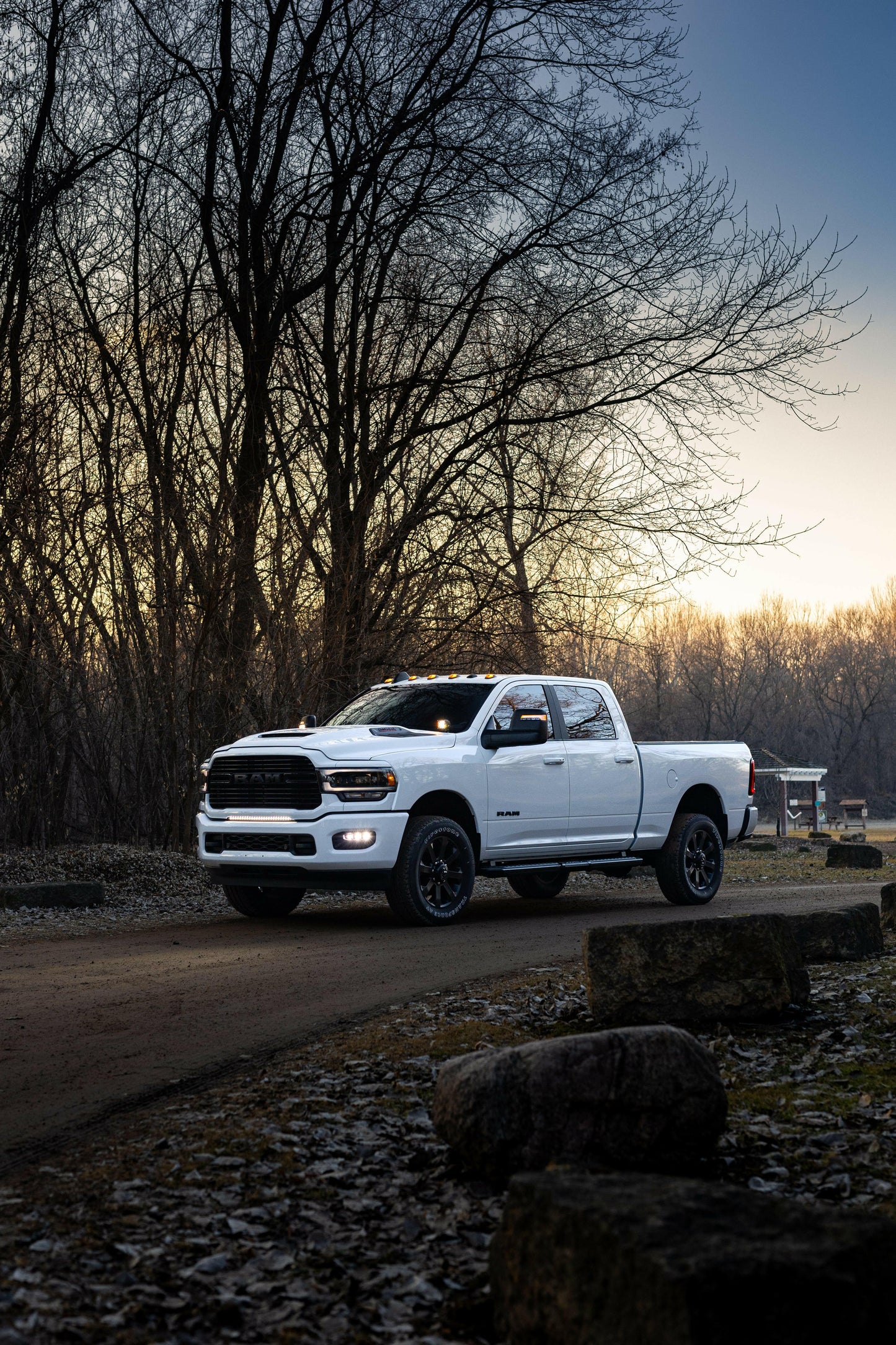 White Ram truck parked on a dirt road with trees and sunset in the background