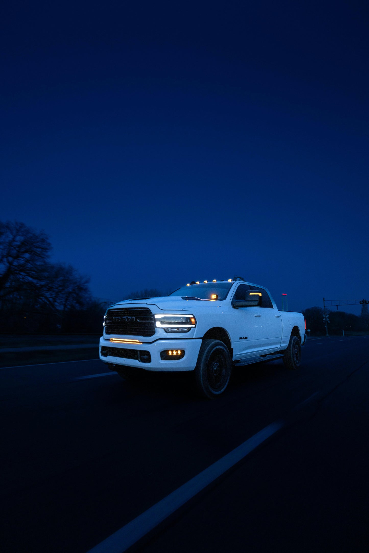 White pickup truck on a dark road at night with headlights and light bar