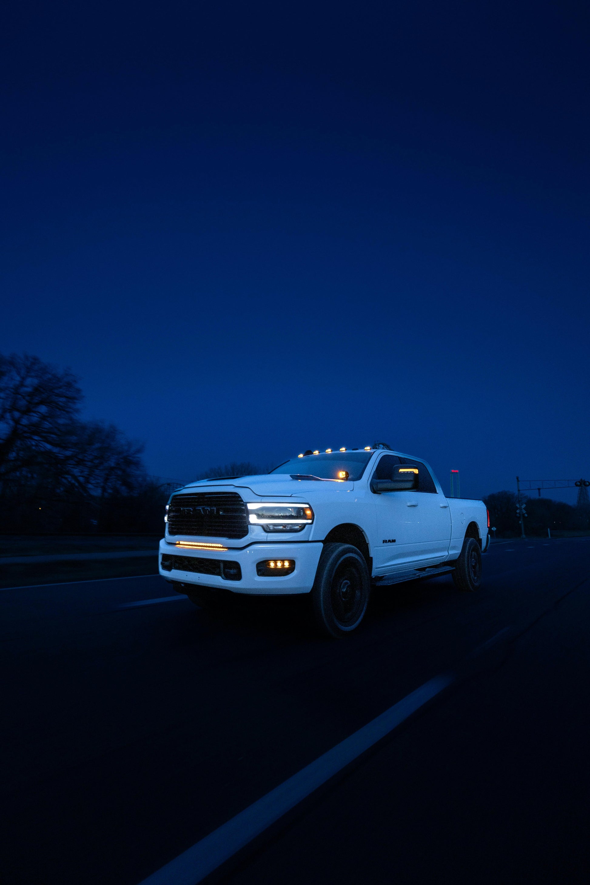 White pickup truck on a dark road at night with headlights and light bar