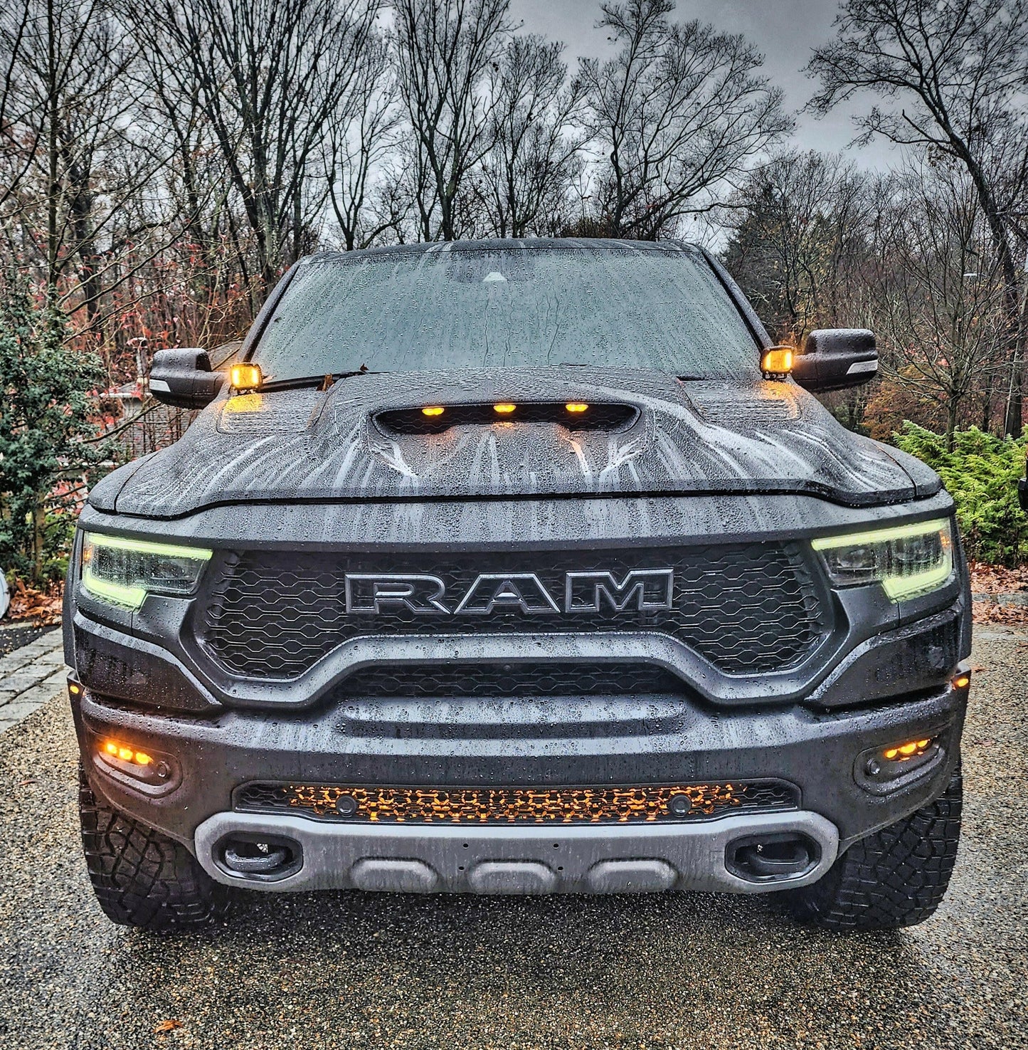 Front view of a Ram truck with visible branding on a road with trees in the background.