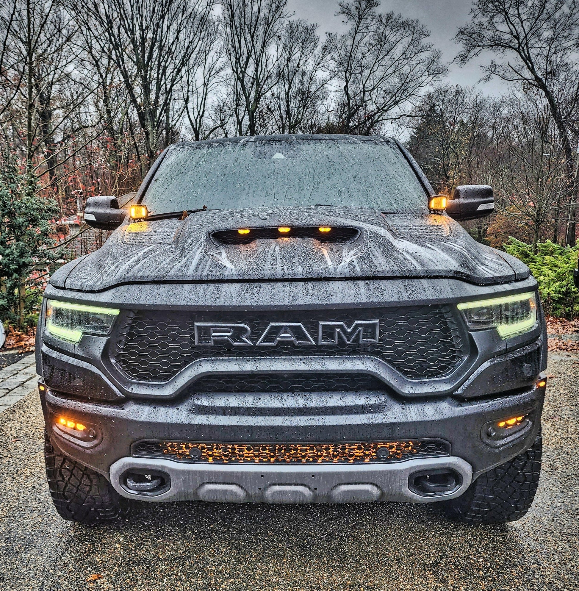 Front view of a Ram truck with visible branding on a road with trees in the background.