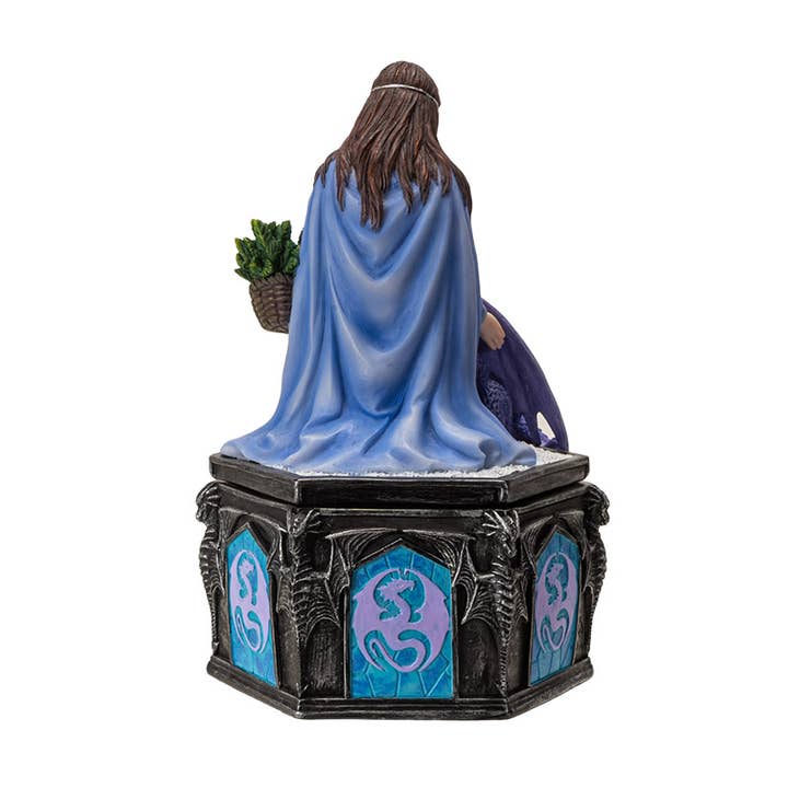 Statue of a figure draped in blue cloth with a plant on a pedestal with decorative panels.