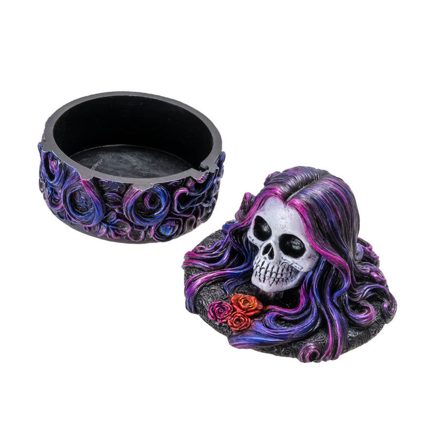 Decorative skull with colorful hair and roses, next to a black bowl on a white background
