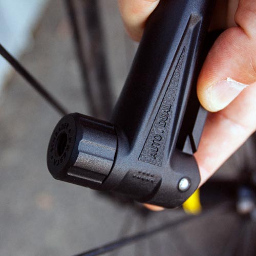 Hand holding a black bicycle pump with a blurred background