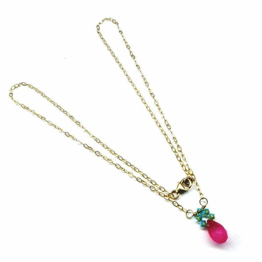Gold necklace with a pink teardrop pendant on a white background