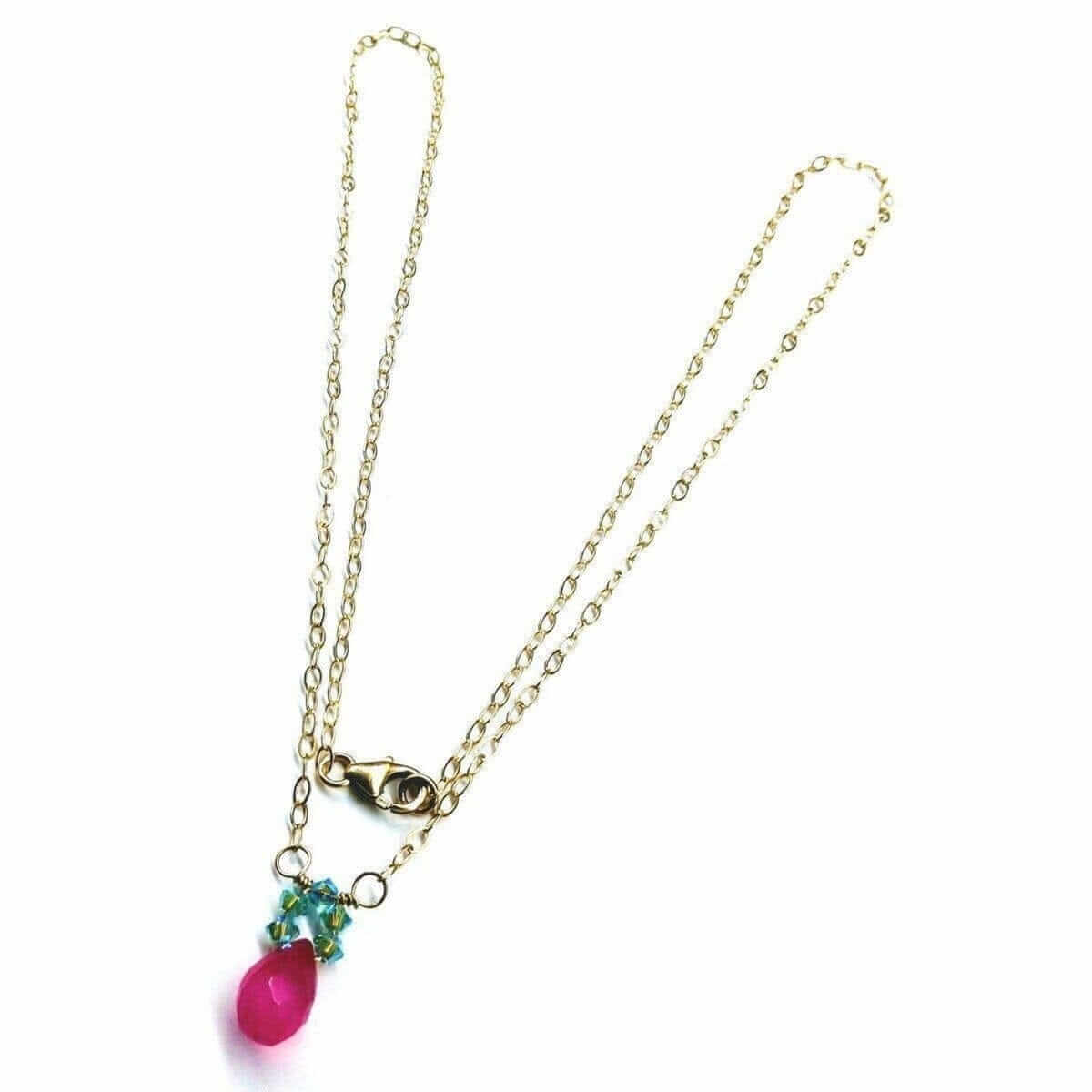 Gold necklace with a pink teardrop pendant on a white background