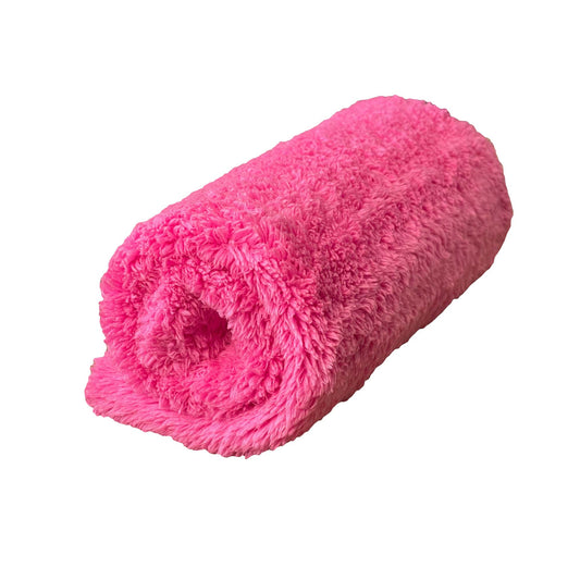 Pink fluffy towel rolled up on a white background