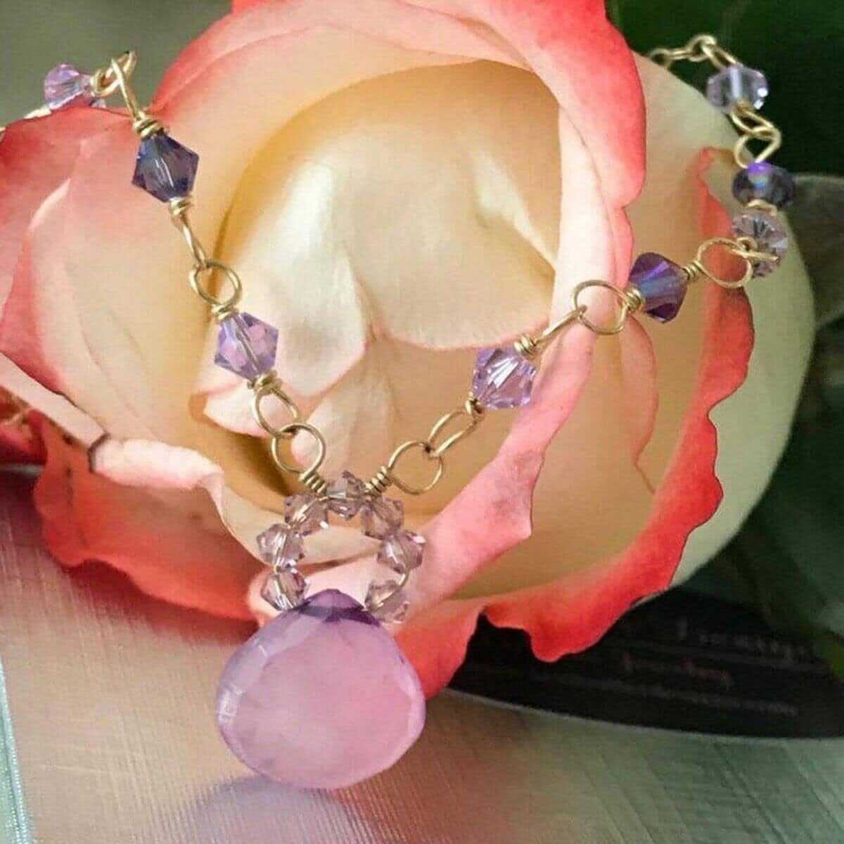 Necklace with purple and clear beads on a pink rose