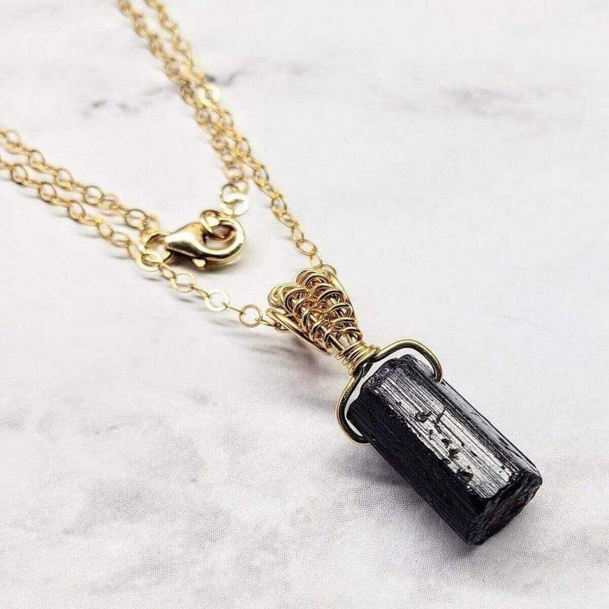 Necklace with a black crystal pendant on a marble surface