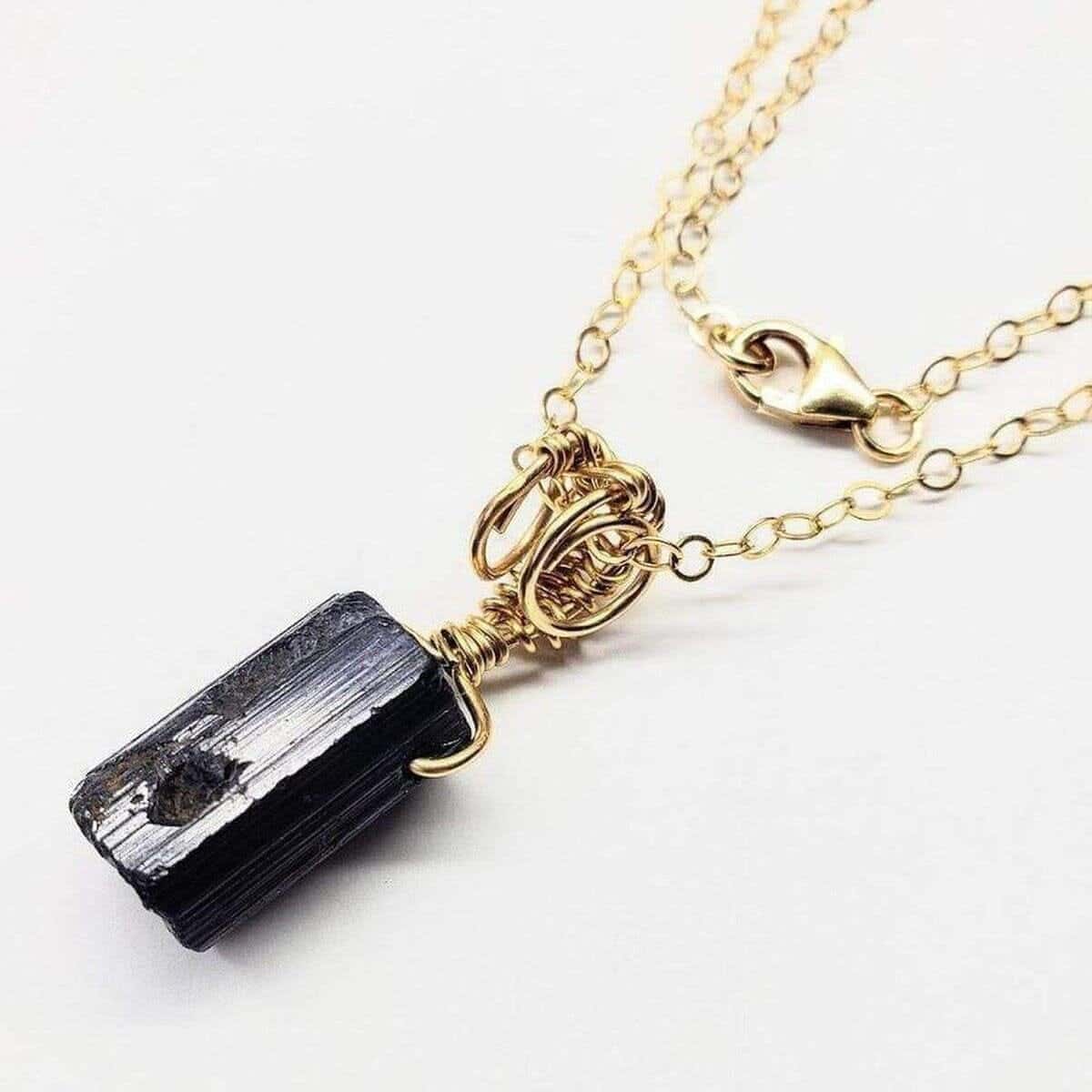 Necklace with a black crystal pendant on a gold chain against a white background