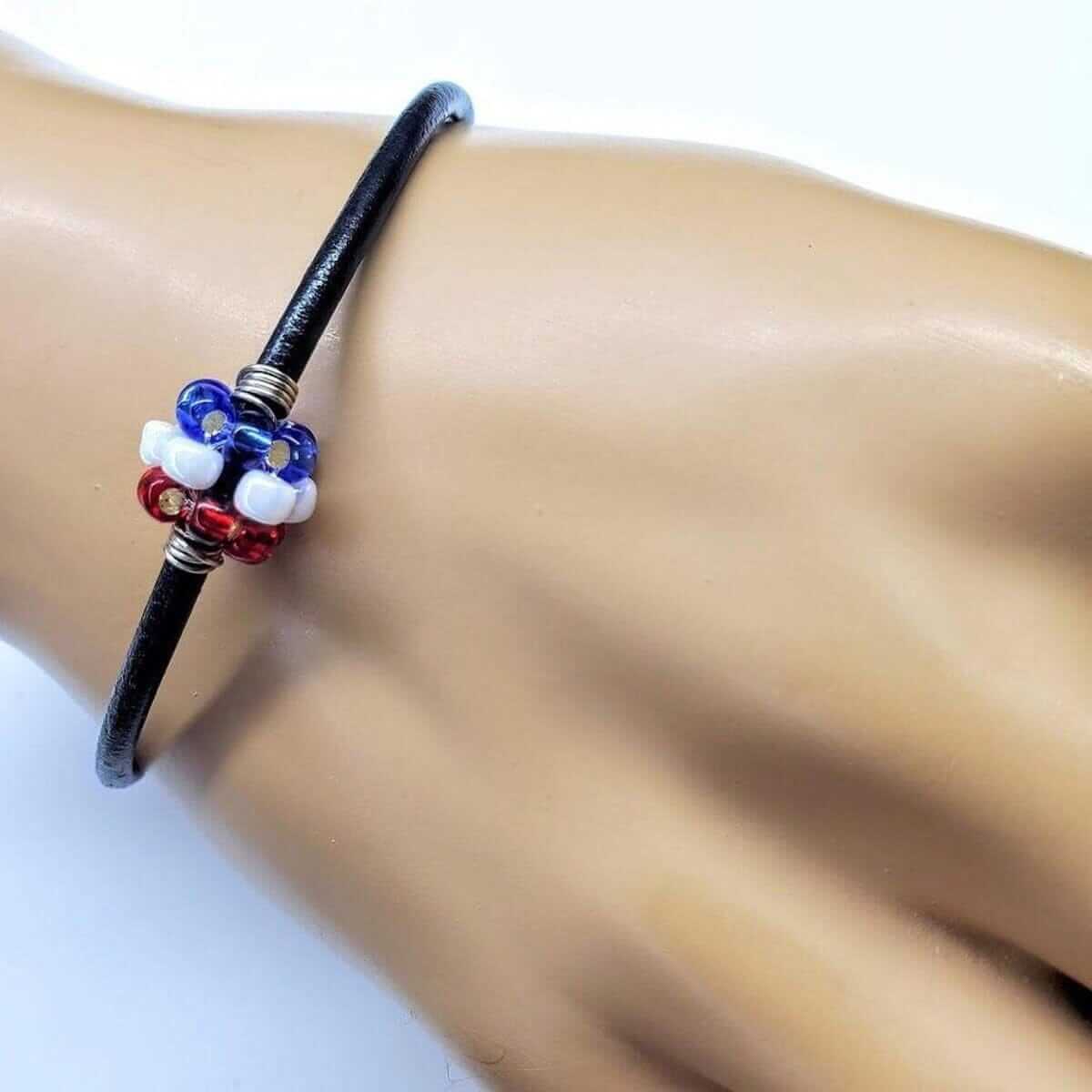 Bracelet with red, white, and blue beads on a wrist against a white background