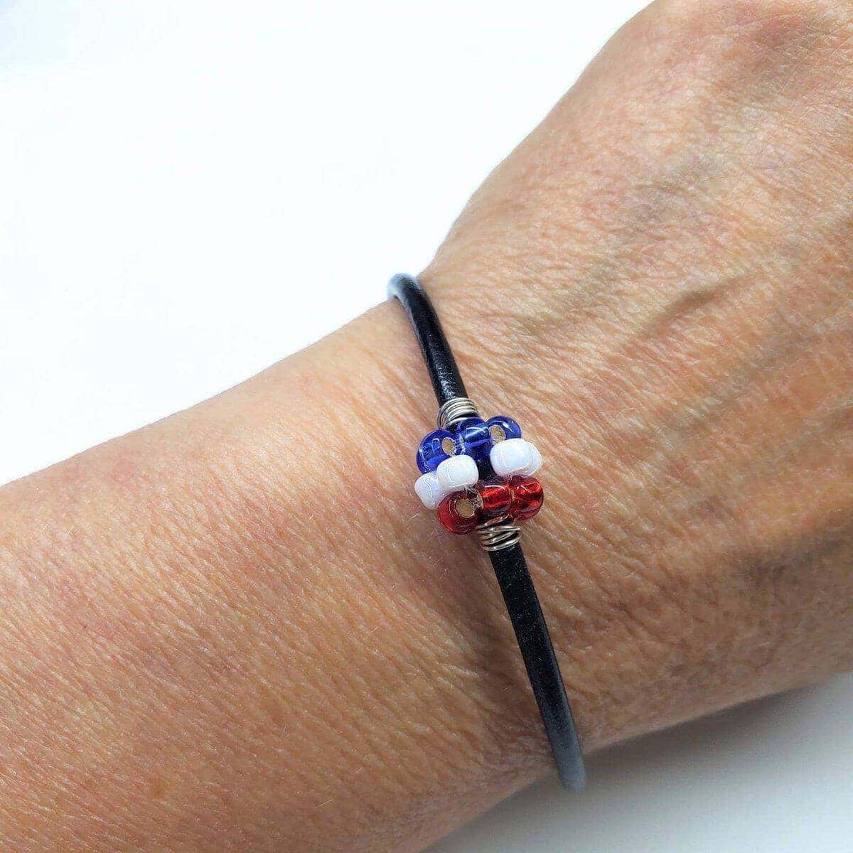 Bracelet with red, white, and blue beads on a wrist against a white background
