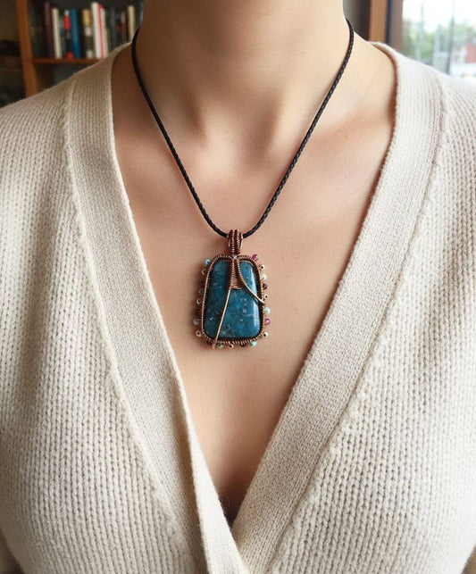 Mannequin wearing a beige sweater with a blue pendant necklace.