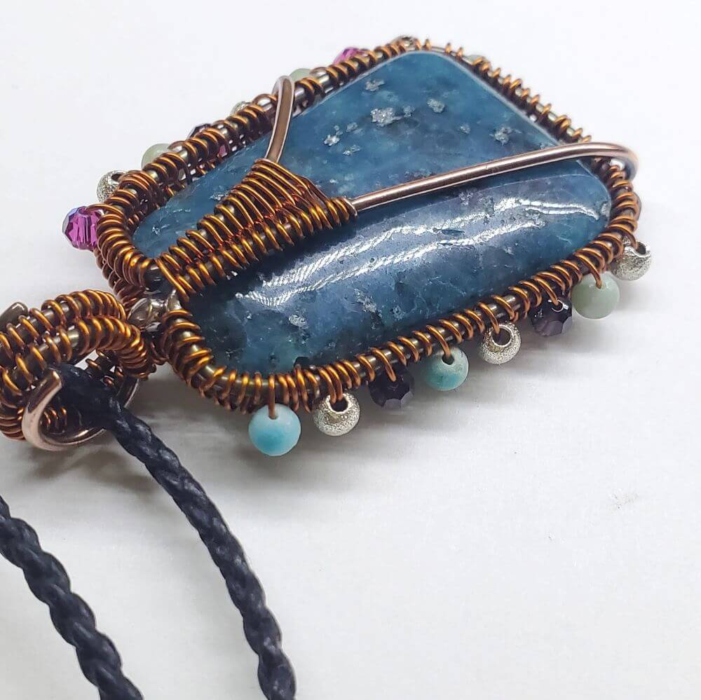 Jewelry with a blue stone and copper wire wrapping on a white background