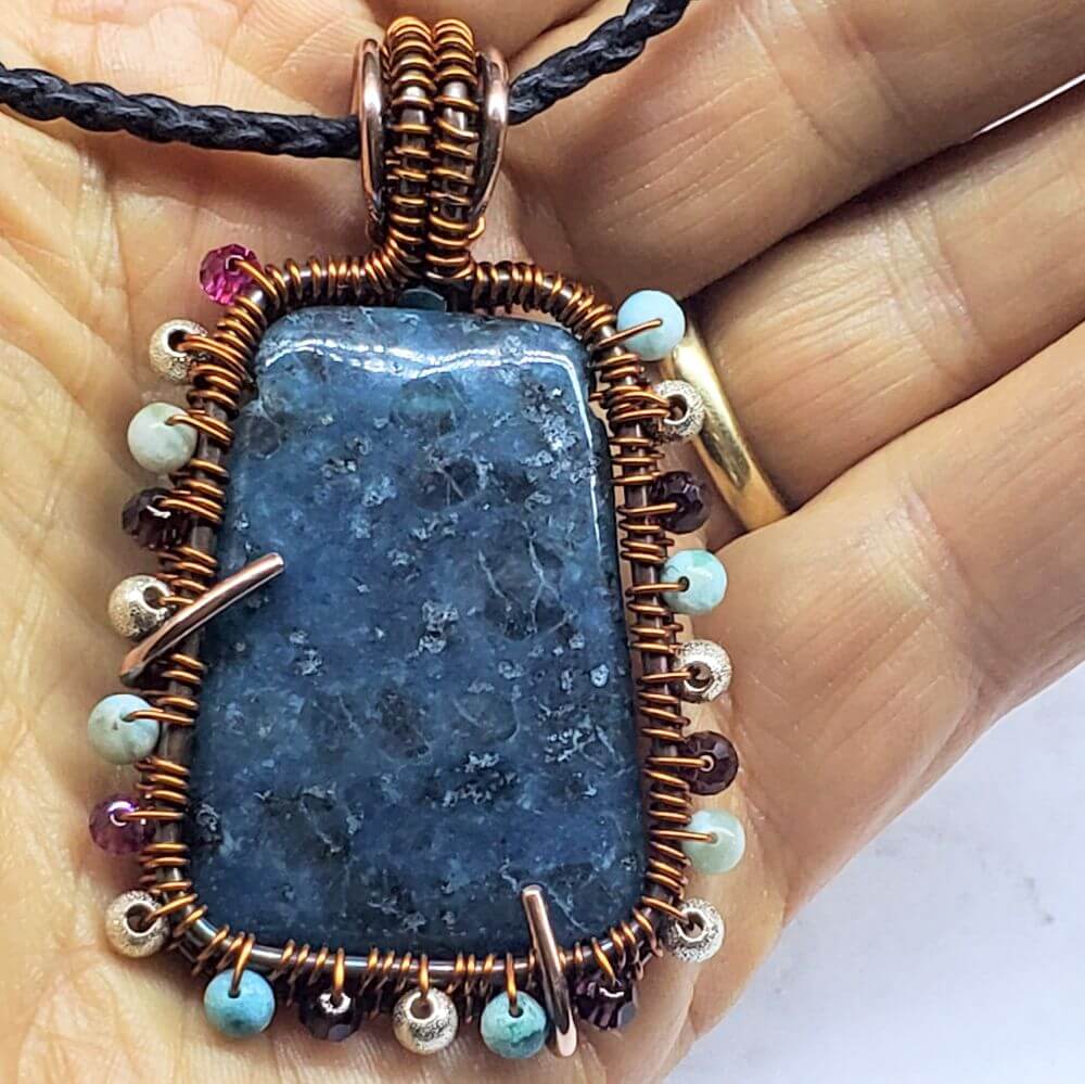Necklace with a blue stone pendant held in a hand