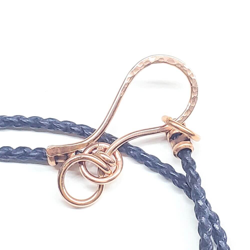 Rose gold clasp on a blue braided cord against a white background