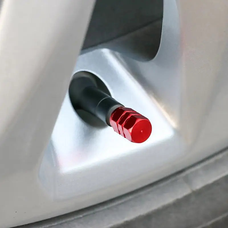 Close-up of a red valve stem cap on a car tire