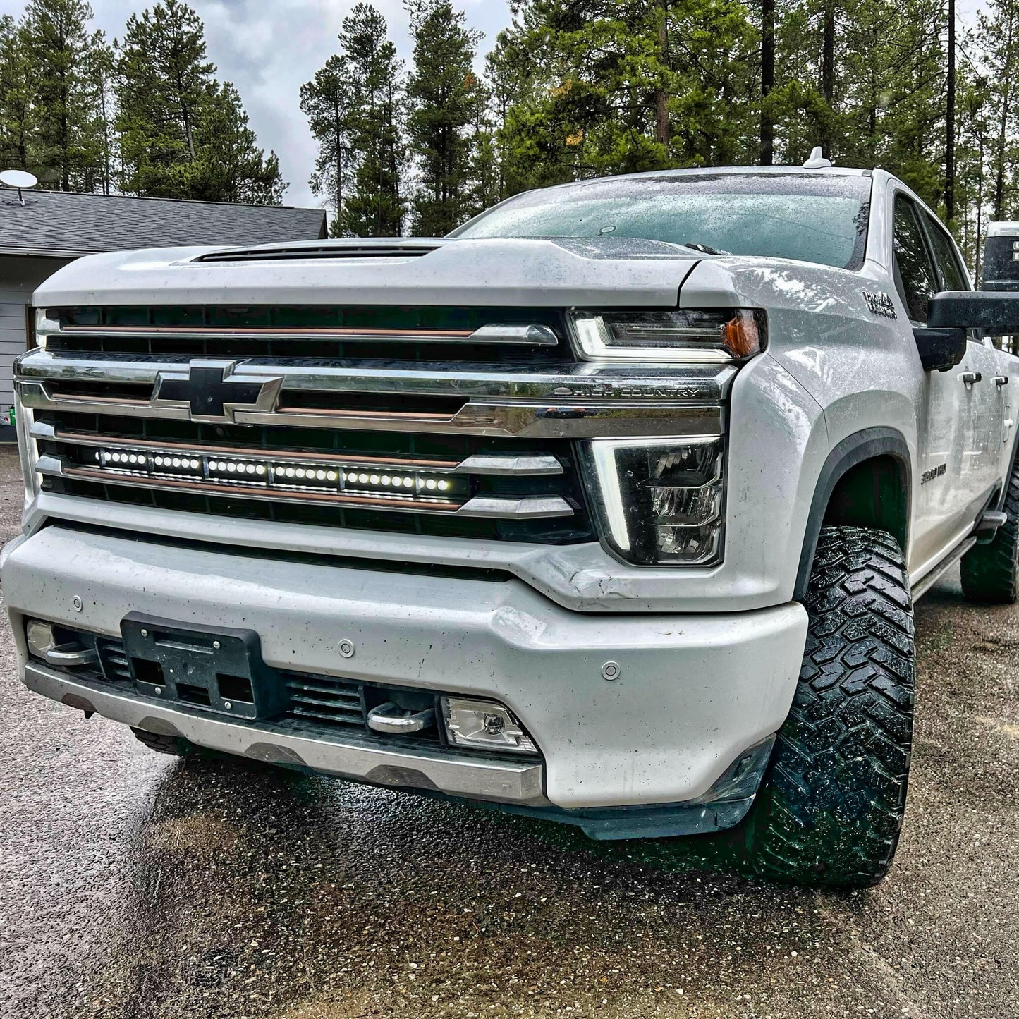 White pickup truck with large tires on a road with trees in the background