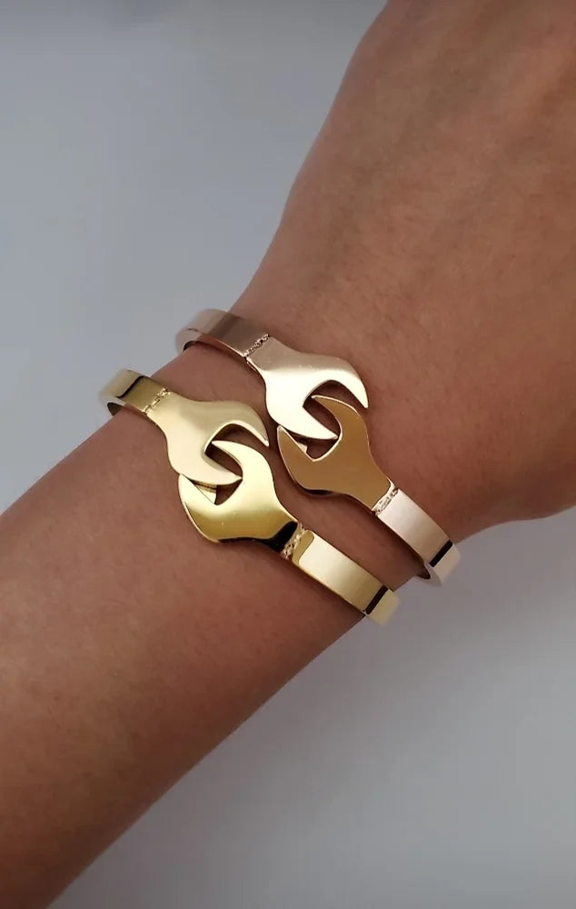 Gold bracelet on a wrist against a neutral background