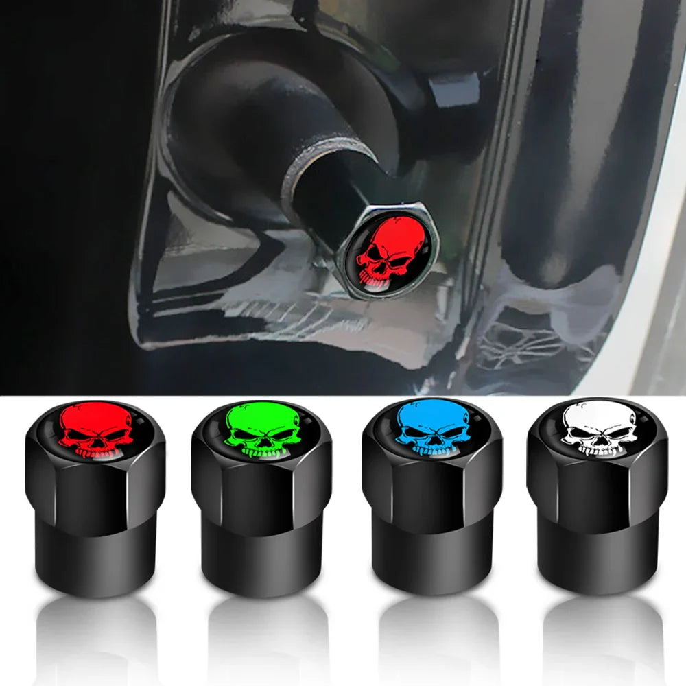 Black skull valve stem caps with red, green, blue, and white designs on a reflective surface.