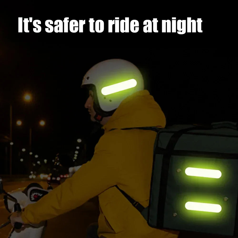 Person wearing a helmet and jacket with reflective lights riding a motorcycle at night.