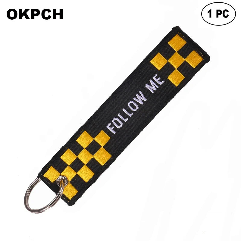 Keychain with yellow and black checkered pattern and 'FOLLOW ME' text on a black background