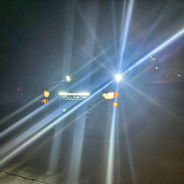 Car headlights shining on a foggy road at night