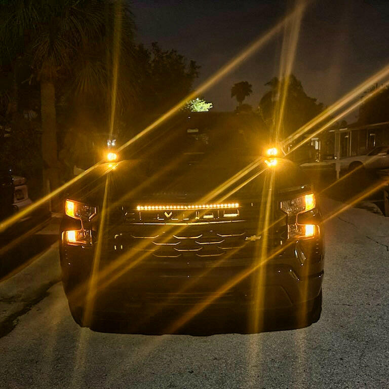 Car with illuminated amber colored headlights and fog lights on a dark road