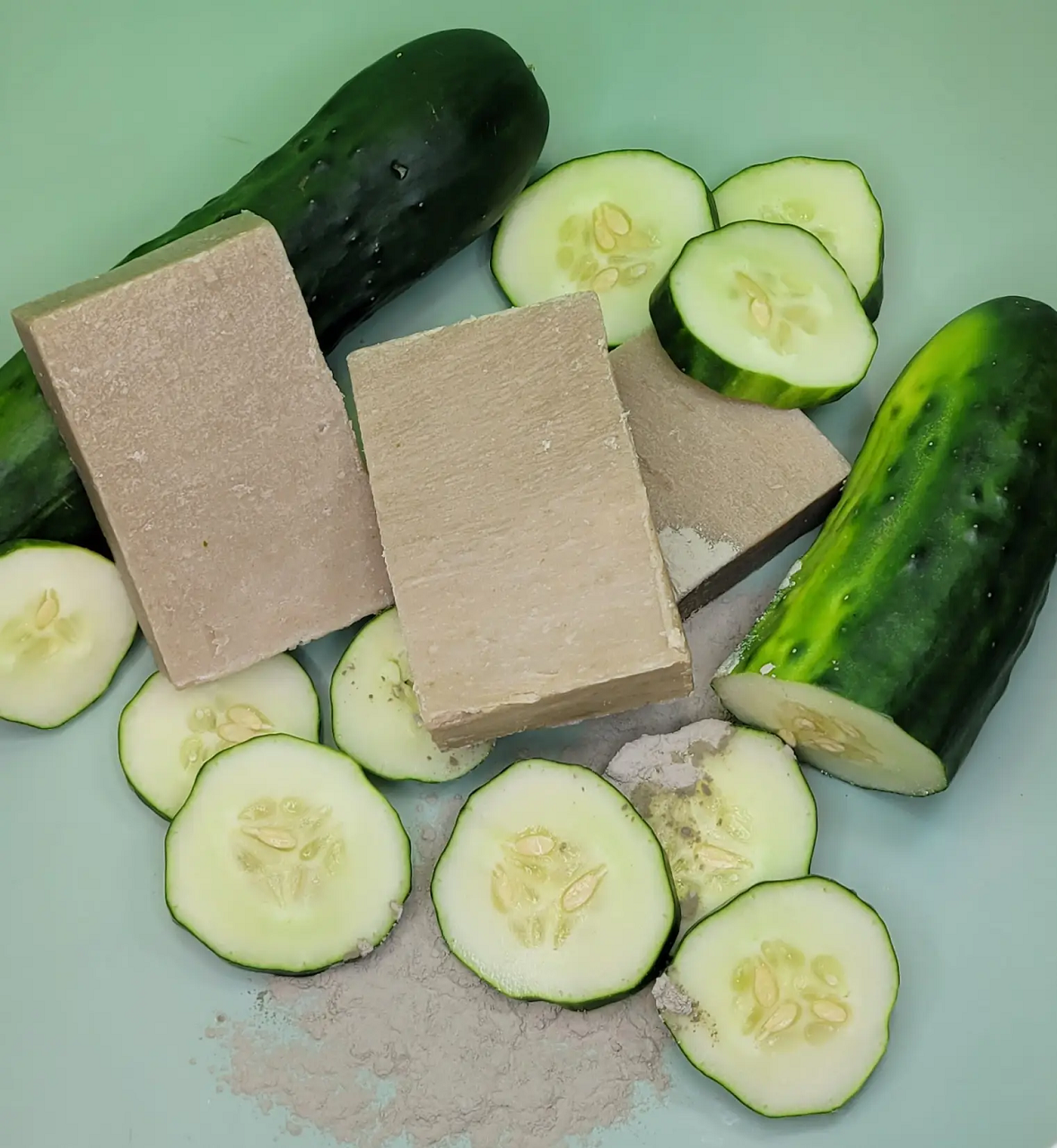 Cucumber slices and soap bars on a light green background