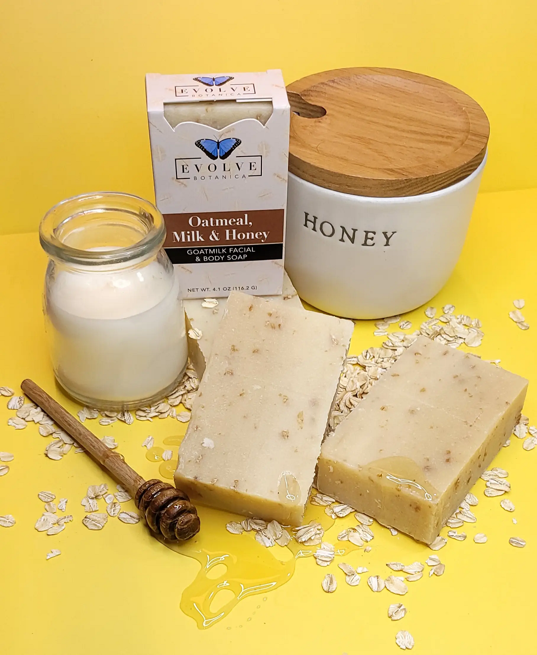 Evolve Oatmeal, Milk & Honey soap with honey jar and candle on a yellow background