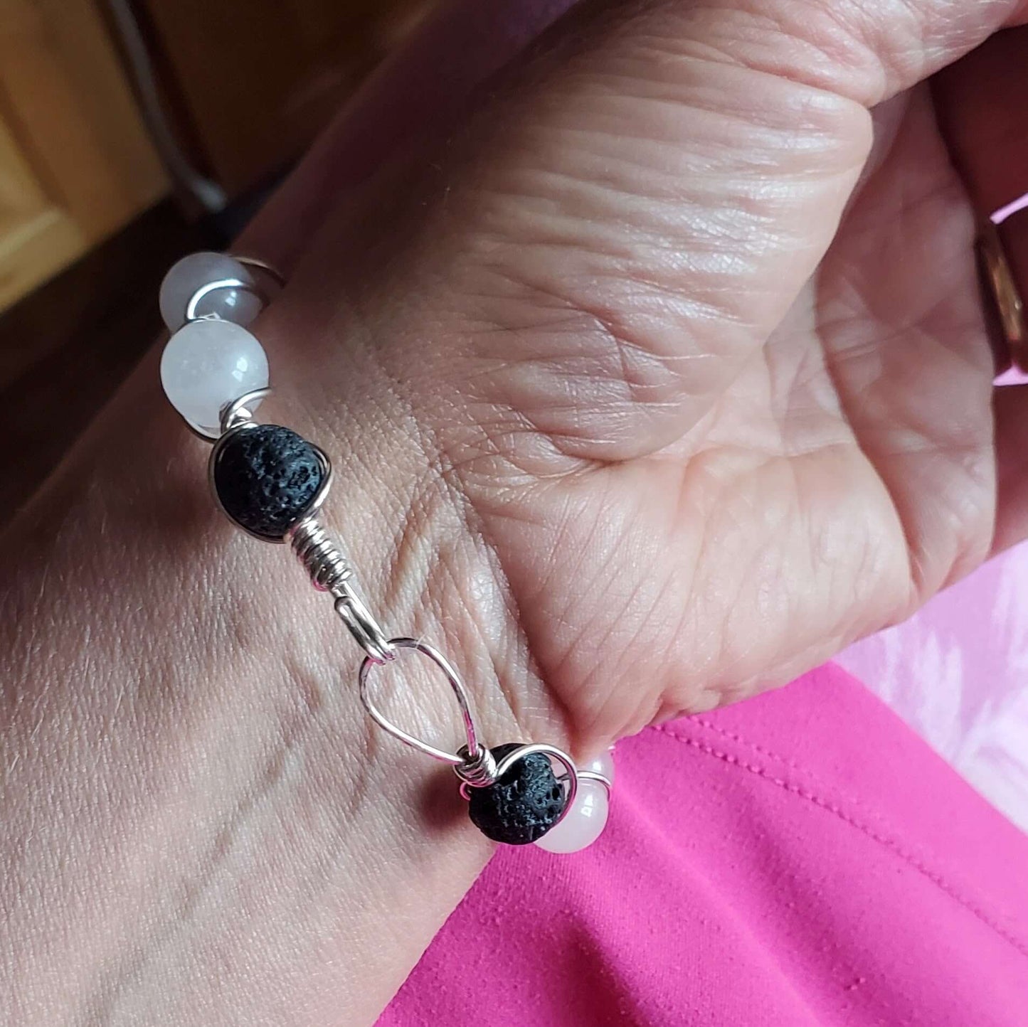 Close-up of a hand wearing a bracelet with black and white beads.