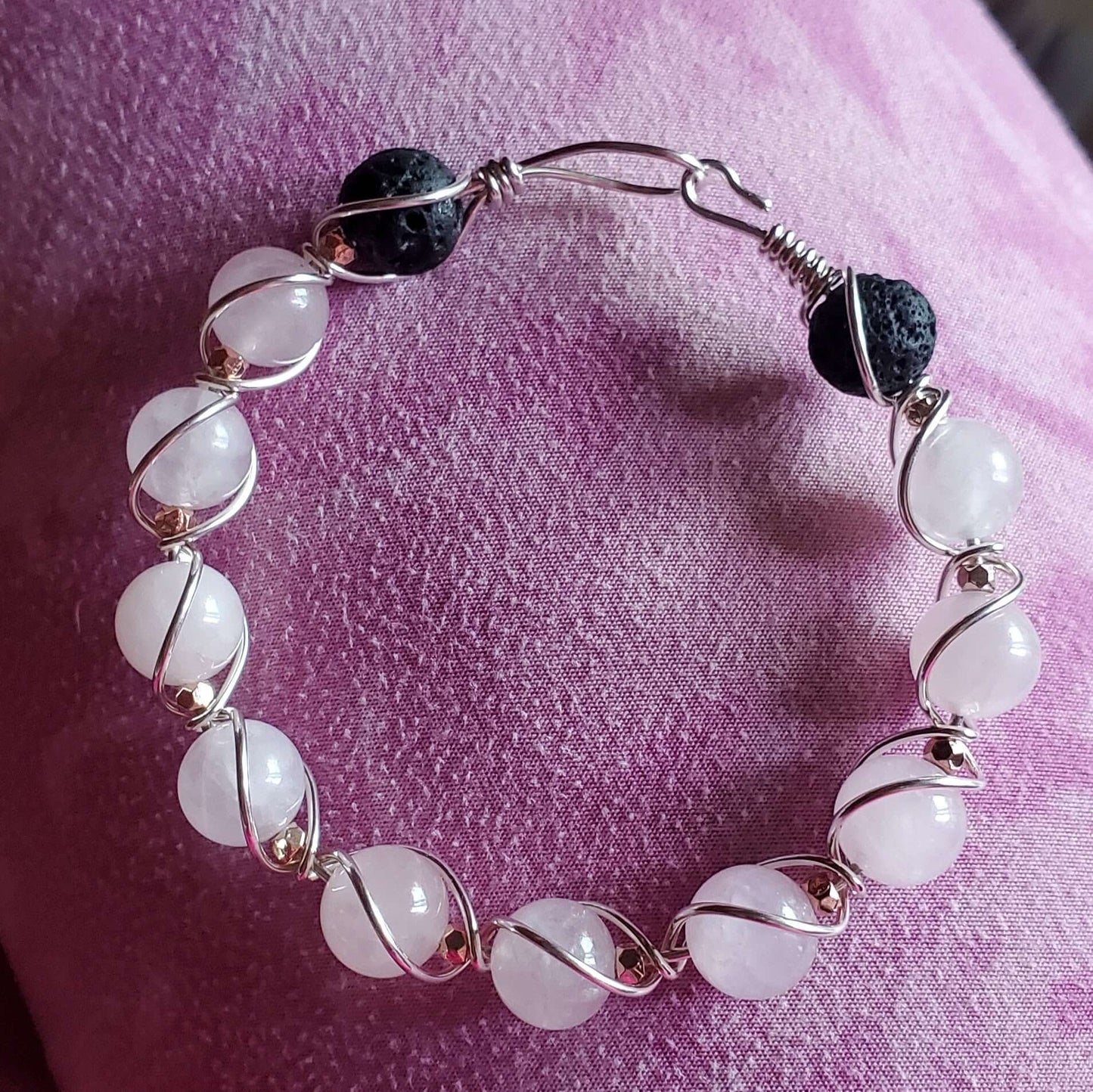 Bracelet with white beads and black stones on a pink fabric background