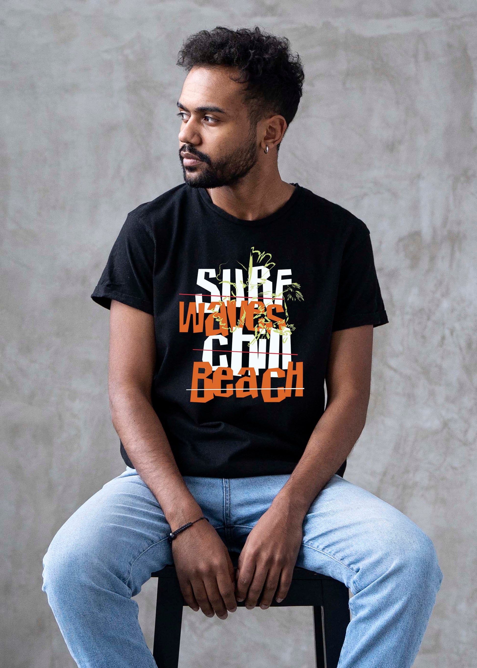 Man wearing a black t-shirt with text and graphics, sitting against a gray concrete wall.