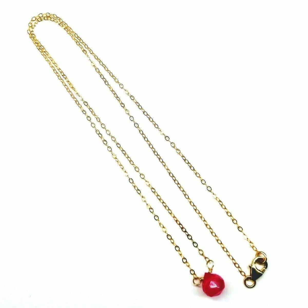 Gold chain necklace with a red bead on a white background