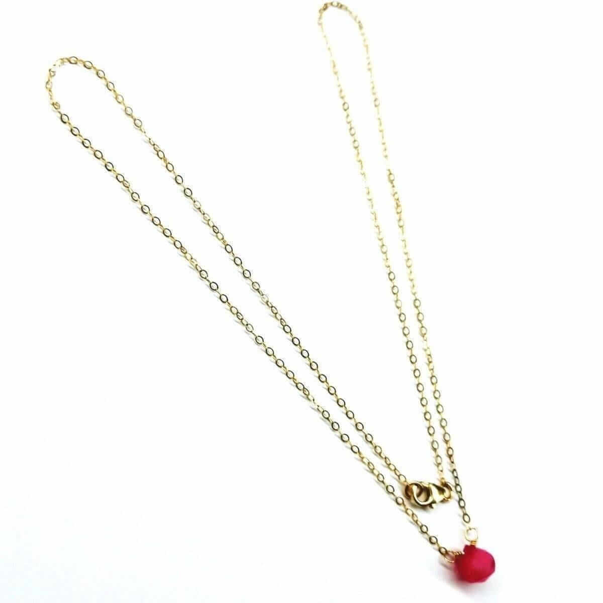 Gold necklace with a red heart pendant on a white background