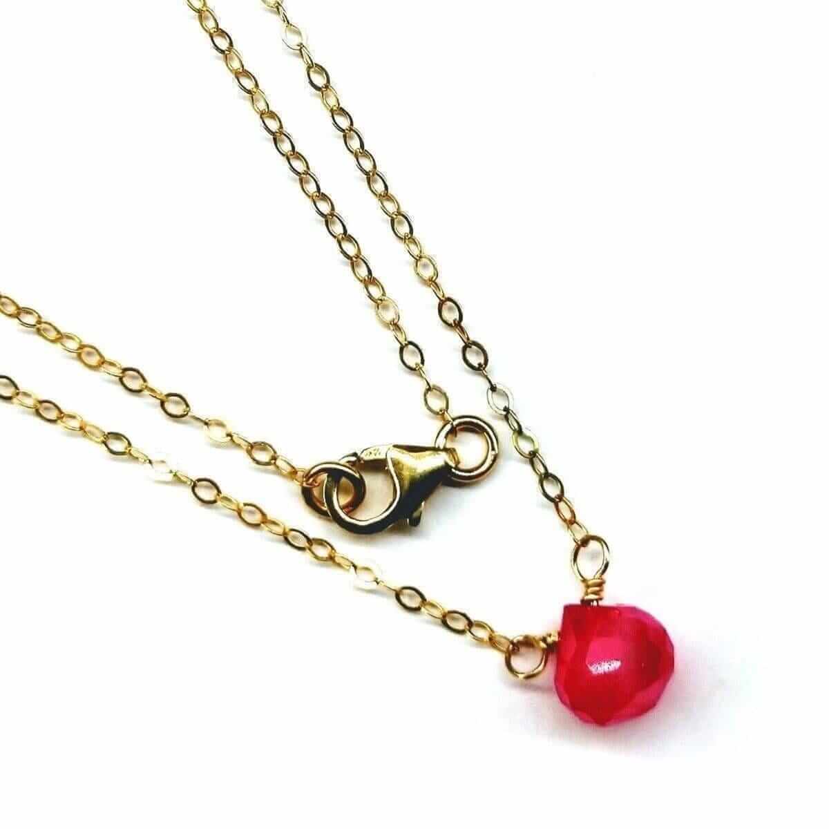 Gold necklace with a red pendant on a white background