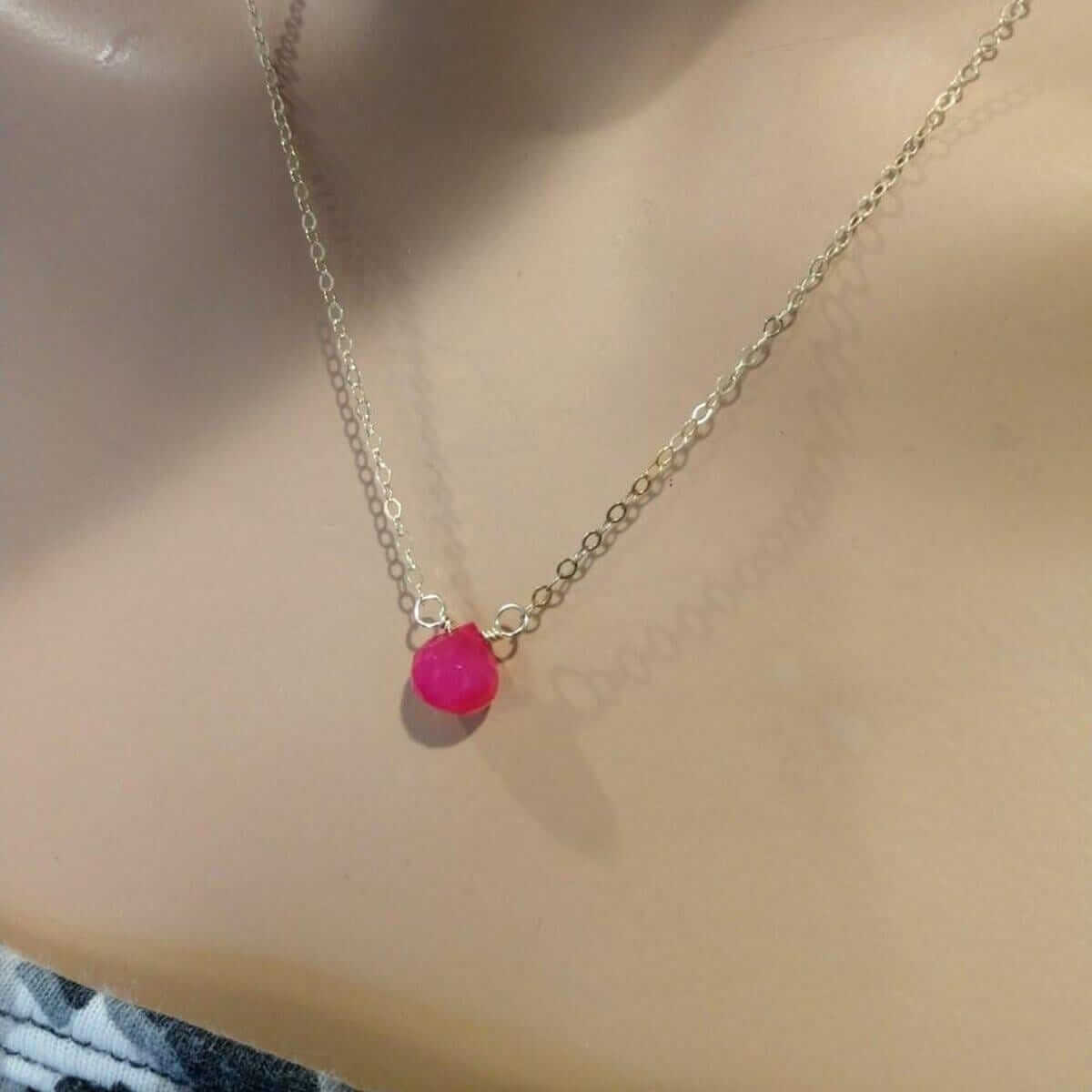 Necklace with a pink bead on a person's neck
