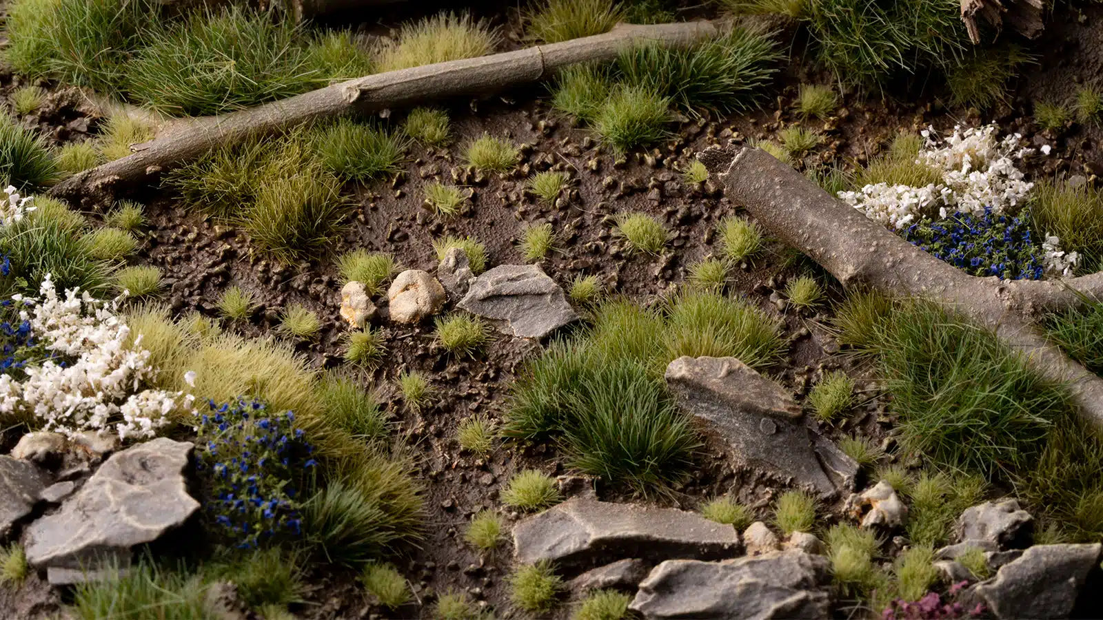 Miniature landscape with grass, rocks, and a log on a dark background