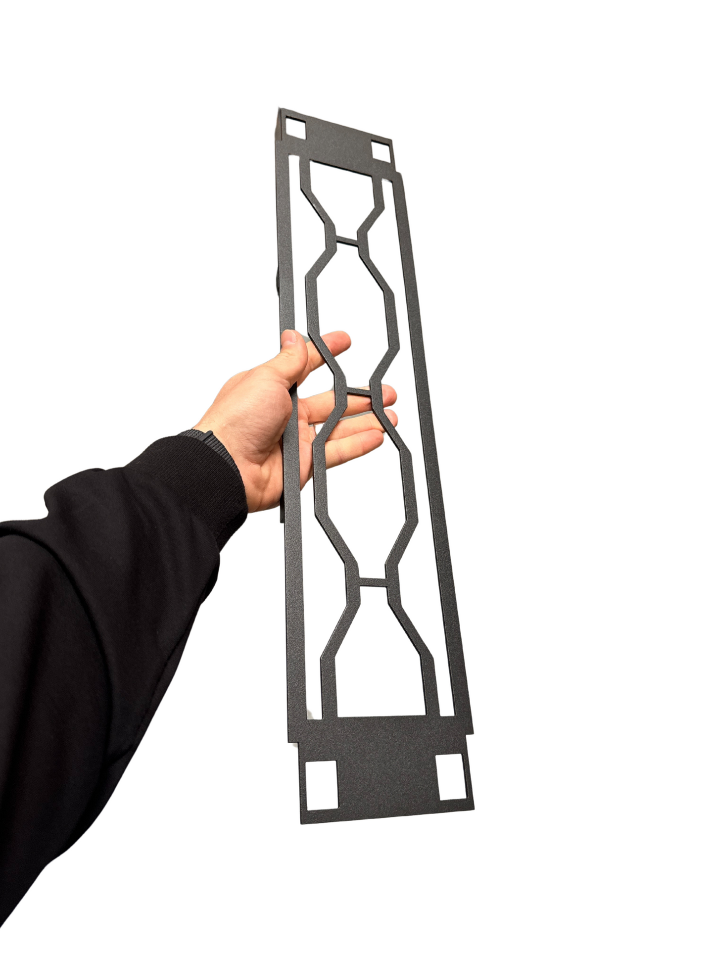 Hand holding a decorative metal grille against a white background