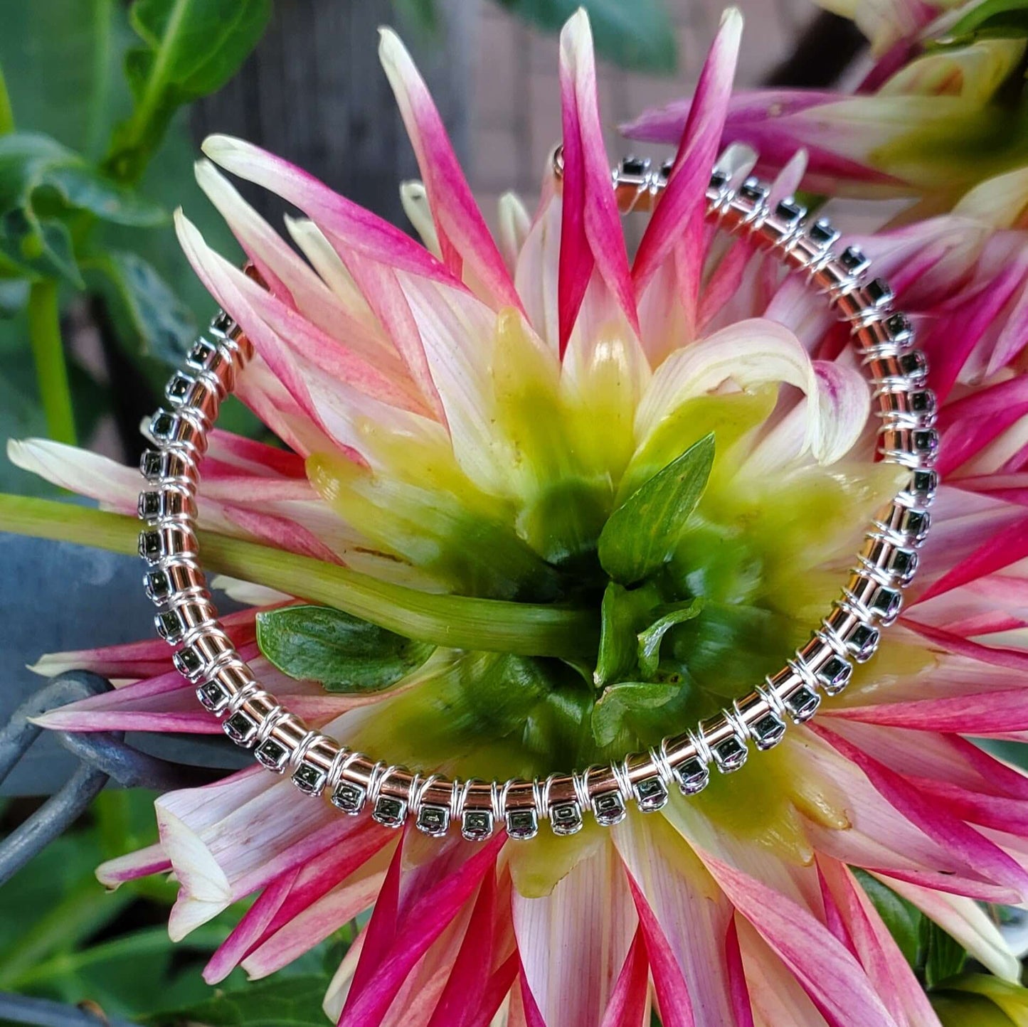 Silver bracelet with black stones on a pink and green flower