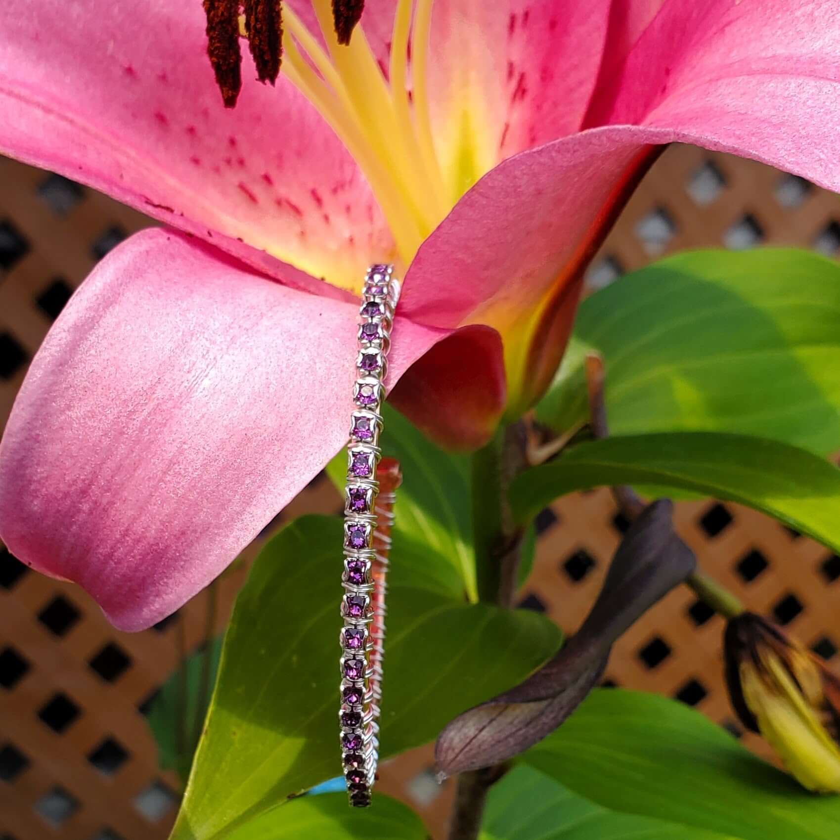 Bracelet with pink gemstones on a pink flower with green leaves