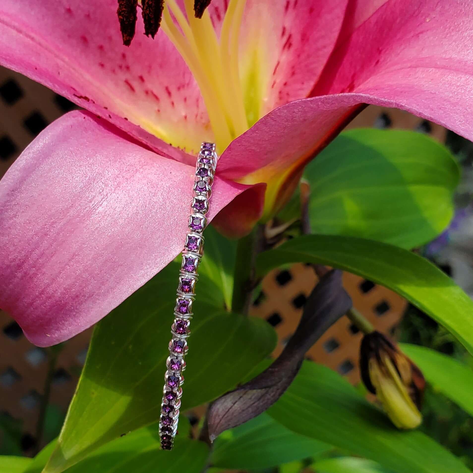 Silver bracelet with purple gemstones on a pink flower