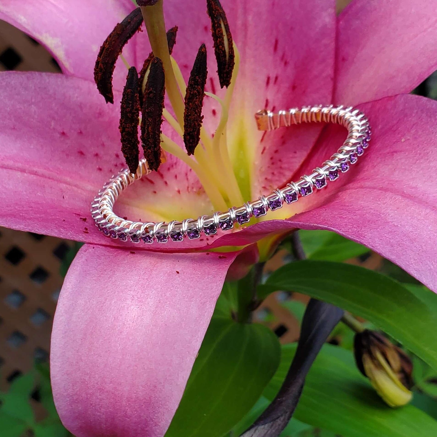 Silver bracelet with purple stones on a pink flower