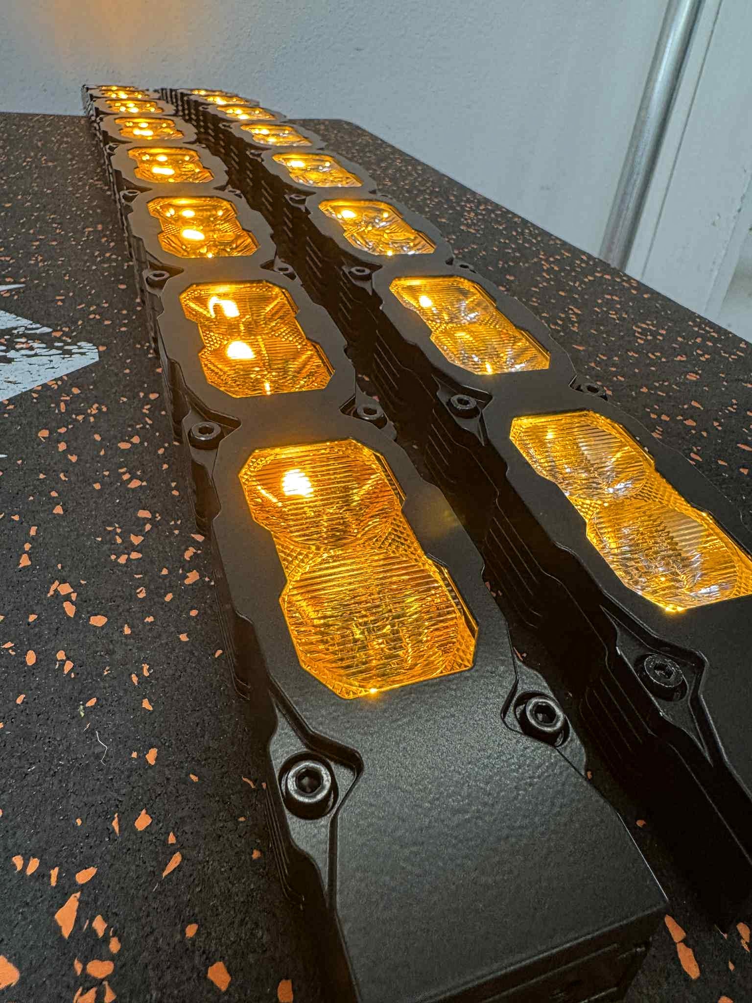 Row of yellow LED lights on a black surface with a white wall background